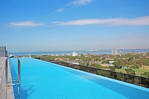 Ein Pool mit Blick auf eine Stadtlandschaft und den Ozean.