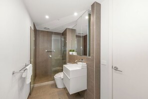 Ein modernes Badezimmer mit Duschkabine aus Glas, einem weißen Waschbecken und einem großen Spiegel.