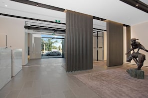Interior moderno com entrada por porta de vidro, uma estátua e piso de azulejos.