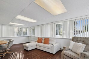 A modern living room with a sectional sofa, a coffee table, and a dining area with chairs. - 4-Bedroom Arnold Retreat | Spacious Yard & Deck (Arnold)