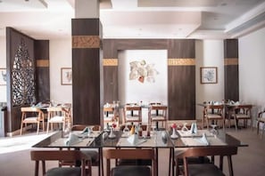 A conference room with multiple tables and chairs, wooden paneling, and framed artwork on the walls.