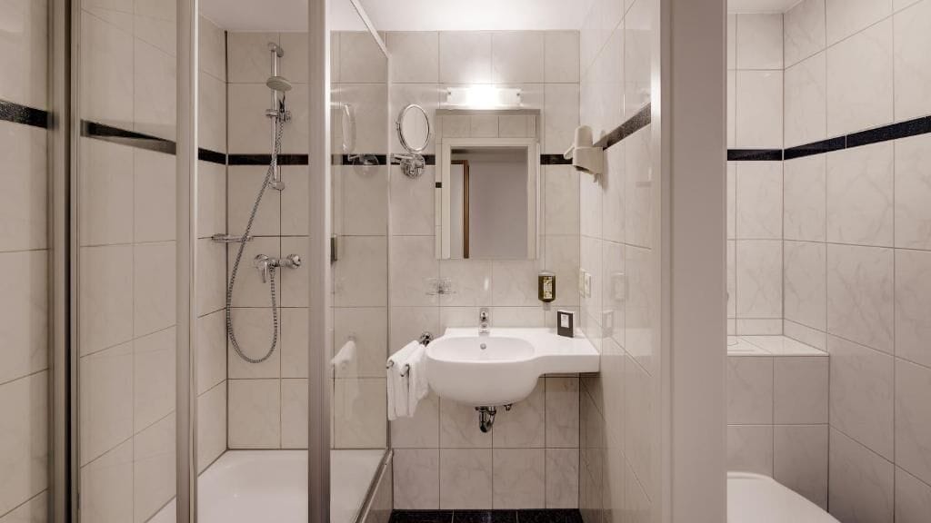 Ein modernes Badezimmer mit einer Duschkabine, einem Waschbecken mit Spiegel darüber und einer Toilette.
