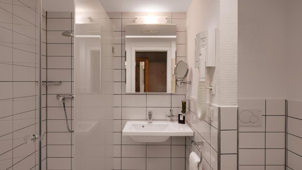 Ein modernes Badezimmer mit Dusche, Waschbecken und Spiegel.
