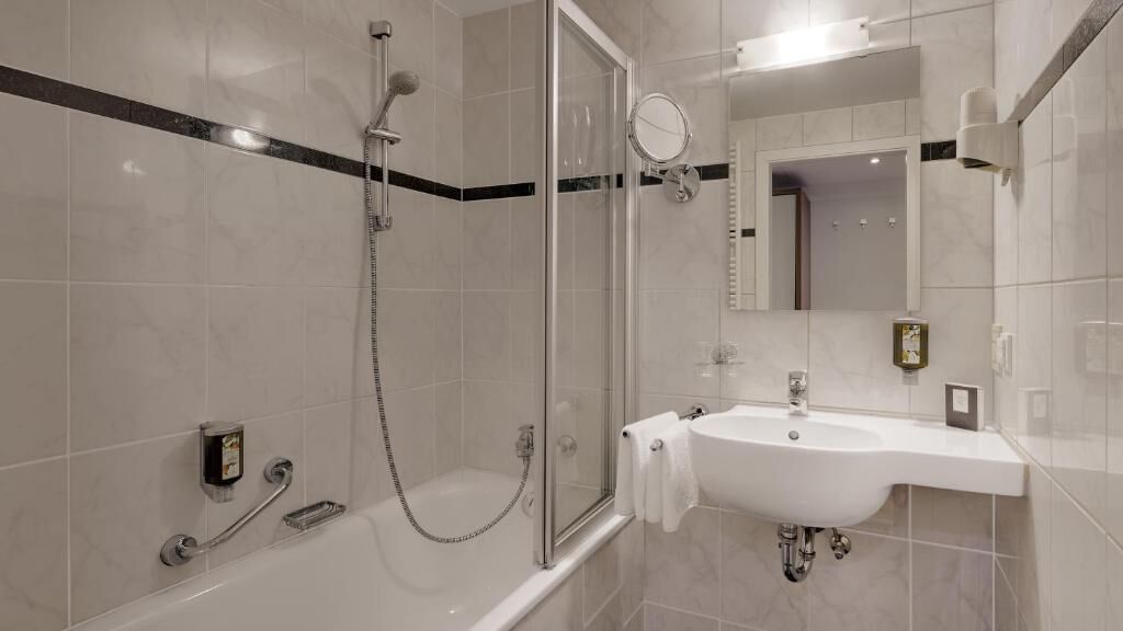 A modern bathroom with a glass-enclosed shower, a white sink, and a mirror.