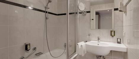 A modern bathroom with a glass-enclosed shower, a white sink, and a mirror.