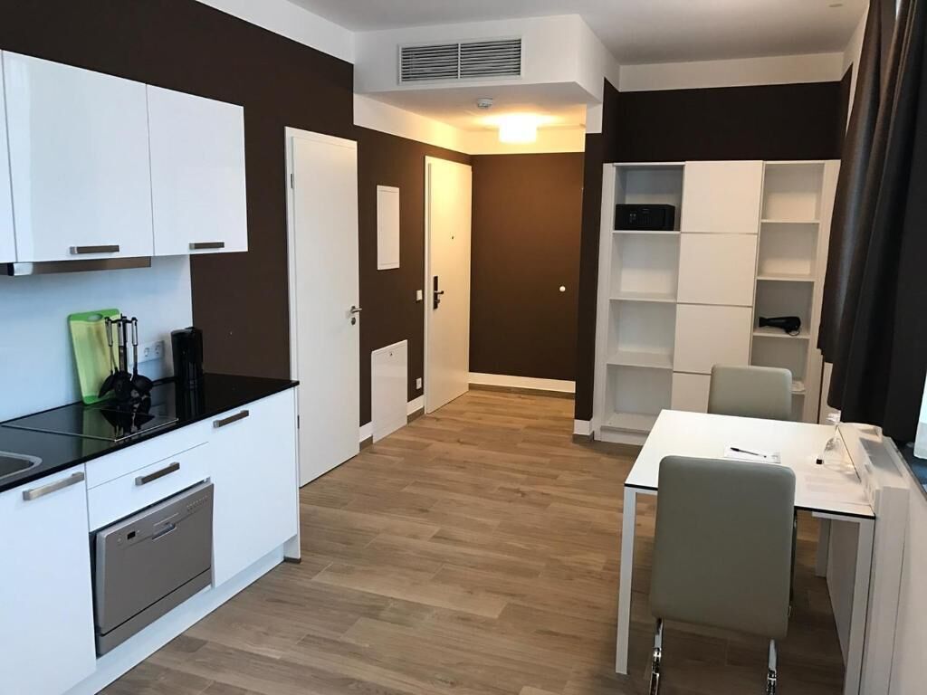 Una cocina moderna con armarios blancos, encimera negra y horno empotrado.