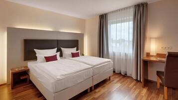 A hotel room with a double bed, a desk, and a chair.