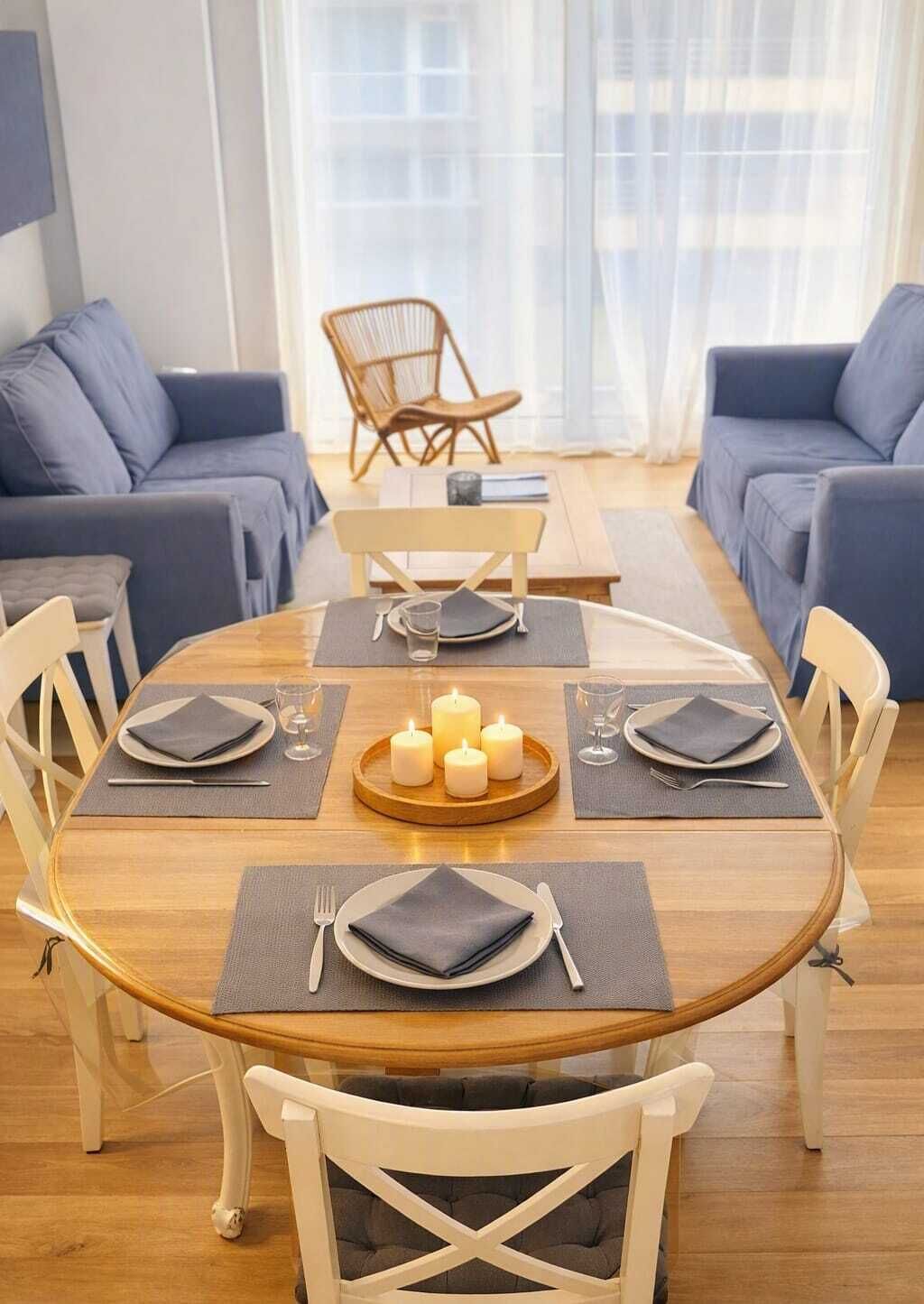 Un comedor con una mesa redonda de madera, seis sillas y un centro de velas.