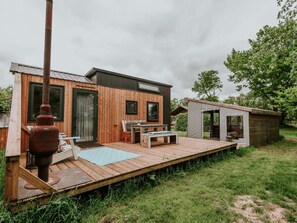 A wooden cabin with a deck, a small outdoor seating area, and a separate wooden structure. - Kampari - Tiny House - Lyts hûs by Interhome (Delfstrahuizen)