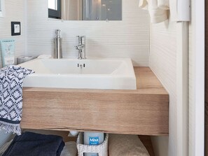 A bathroom with a white sink, wooden countertop, and a mirror above it. - Kampari - Tiny House - Lyts hûs by Interhome (Delfstrahuizen)