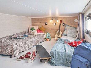 A bedroom with two beds, a guitar, a skateboard, and various personal items. - Kampari - Tiny House - Lyts hûs by Interhome (Delfstrahuizen)