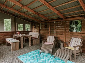 A rustic wooden room with a table, chairs, and a patterned rug. - Kampari - Tiny House - Lyts hûs by Interhome (Delfstrahuizen)