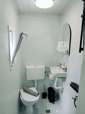 Un bany petit i blanc amb vàter, bidet i rentapisa.