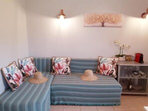 A room with a striped sofa, decorative pillows, a wall-mounted light fixture, a framed artwork, and a glass cabinet with dishes. - Aloni House Kokkini Corfu (Kokkini, Corfu)