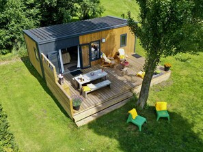 A modern wooden cabin with a deck, outdoor seating, and a small garden area. - Kampari - Tiny house - Praathuis by Interhome (Delfstrahuizen)