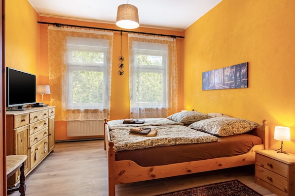 A bedroom with a bed, a television, a dresser, and a painting on the wall.