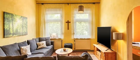 A living room with a sofa, a coffee table, a TV, and a cross on the wall.