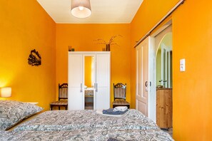 Ein Schlafzimmer mit zwei Betten, einem weißen Wandschrank, einem Holzstuhl und einem kleinen Tisch mit Blumenvase.
