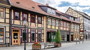 A street with traditional half-timbered buildings, a food house, and a green tree in the center.