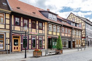 Eine Straße mit traditionellen Fachwerkhäusern, einem Gastronomiehaus und einem grünen Baum in der Mitte.