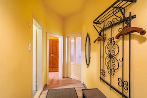 A hallway with yellow walls, wooden doors, and a metal rack with decorative items.