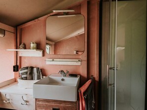 A bathroom with a white sink, a mirror, and a shower door. - Kampari - Luxe Safaritent - De Jungle by Interhome (Delfstrahuizen)