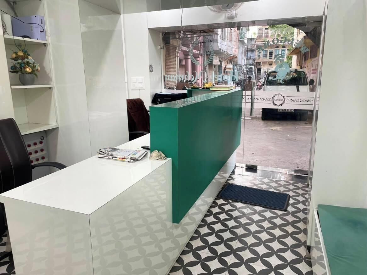 A reception area with a white desk, a green counter, and patterned floor tiles.