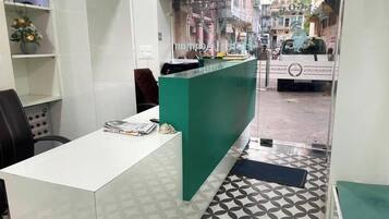 A reception area with a white desk, a green counter, and patterned floor tiles.