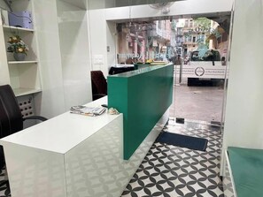 Zona de recepción con un escritorio blanco, un mostrador verde y baldosas de suelo con diseños.