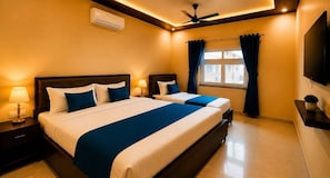 Een hotelkamer met twee bedden, een plafondventilator, een airconditioning, een televisie en een raam met gordijnen.
