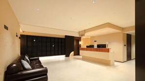 Un hall de hotel con mostrador de recepción, una zona de estar con sofá y un panel en la pared.
