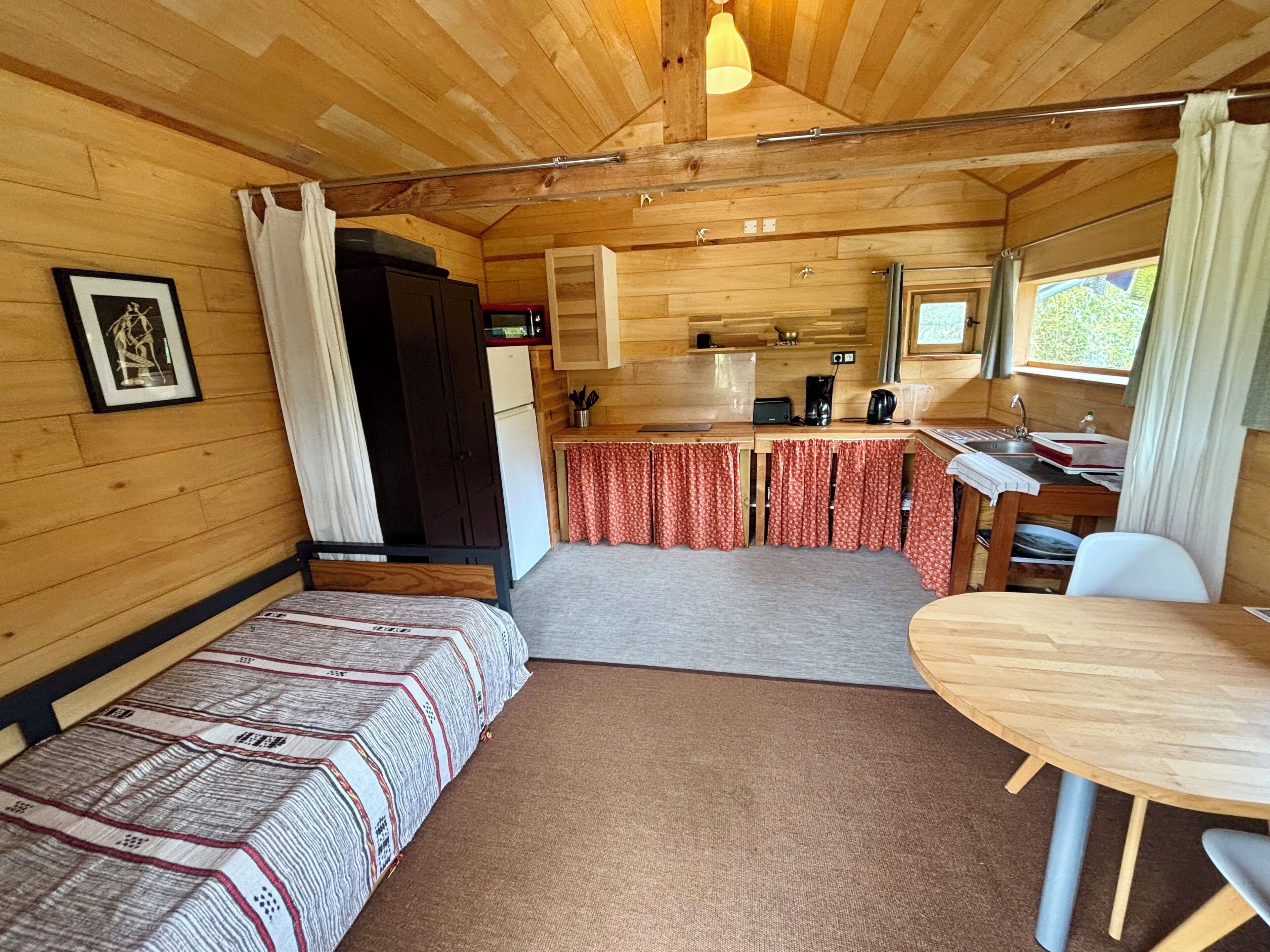 Una cabaña compacta con kitchenette, comedor y cama con colcha estampada.