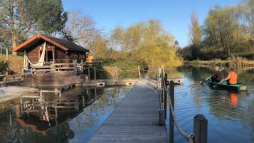 A wooden dock leading to a cabin with a small deck and a rope barrier.