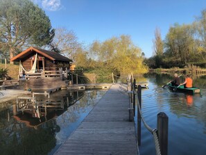 A wooden dock leading to a cabin with a small deck and a rope barrier.