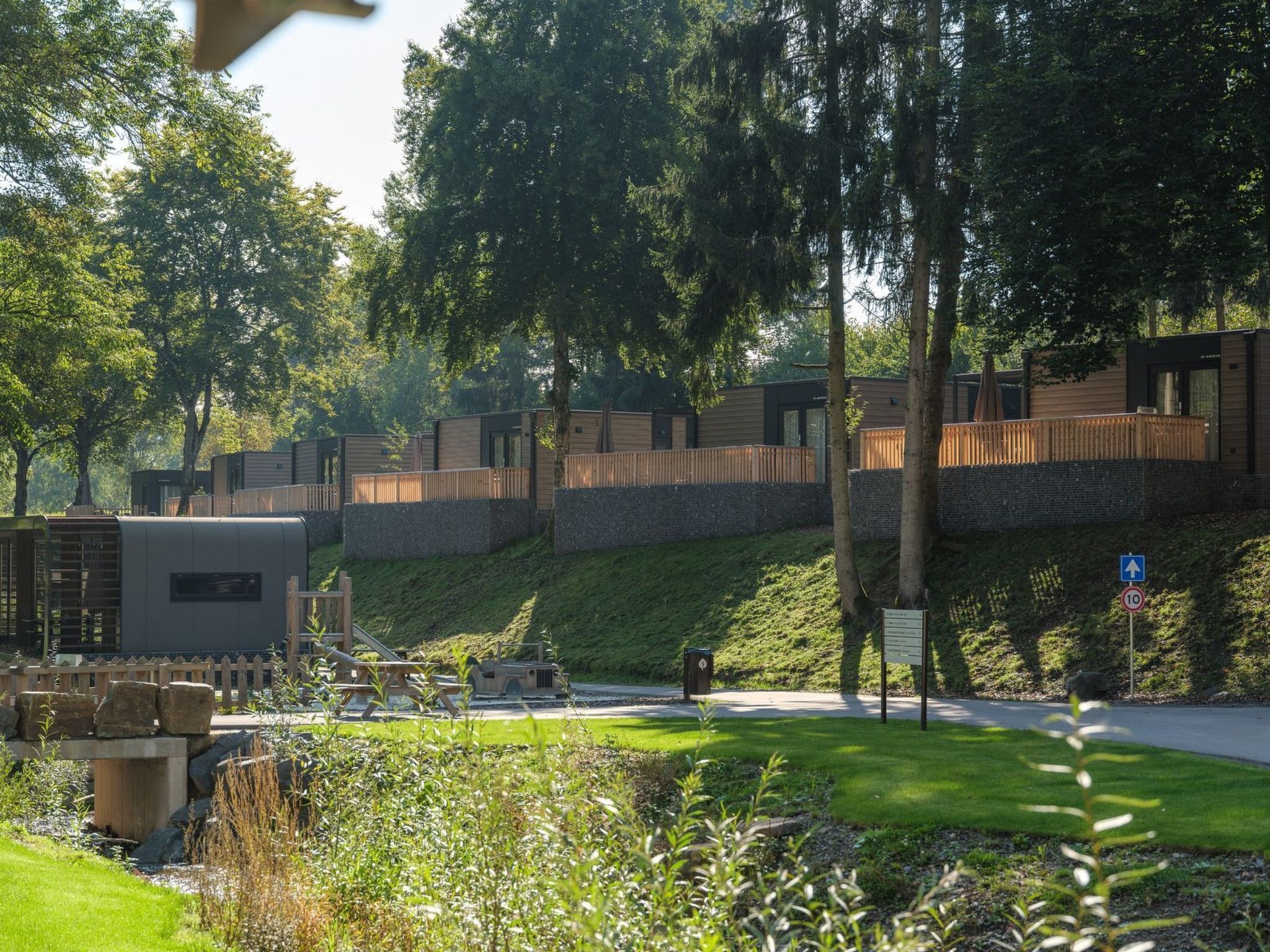 Un quartiere residenziale con case moderne, una strada asfaltata e un'area verde alberata.