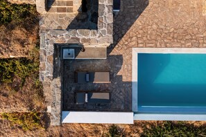 An aerial view of a pool area with a stone deck, a small sink, and two sun loungers. - Magical Sunsets & Stunning Panoramic Views (Tinos)