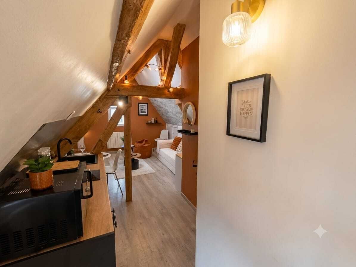 A modern kitchen with a built-in grill, wooden beams, and a cozy seating area with a sofa and cushions.