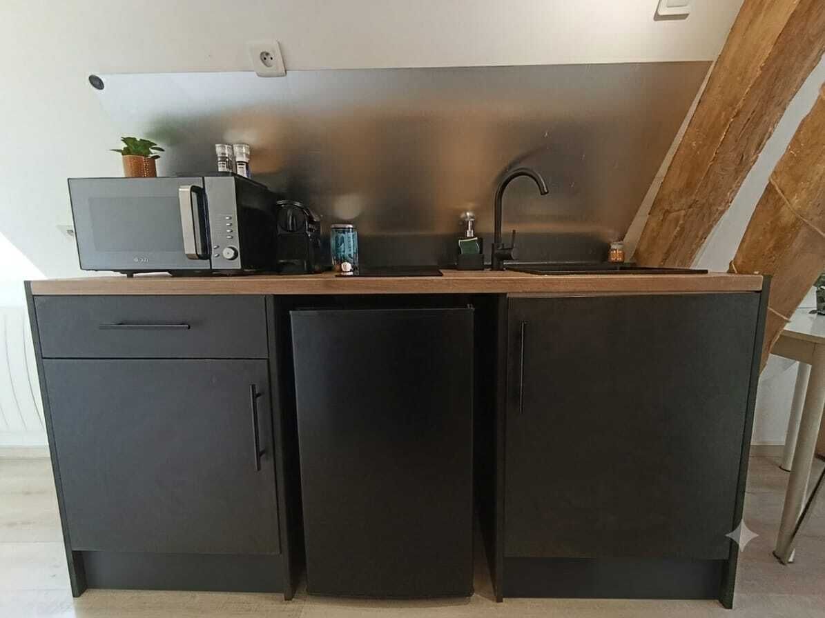 A compact kitchenette with a microwave, coffee maker, and a sink.