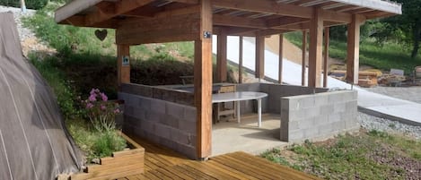 A wooden pergola structure with a built-in seating area and a table.