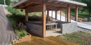 Una estructura de pergola de fusta amb zona d'estar integrada i una taula.
