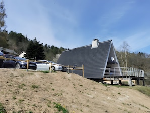 A modern house with a sloped roof, a visible chimney, and a car parked in front.