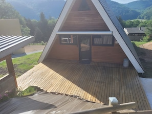 A wooden deck with a triangular roof structure, a door, and a window.