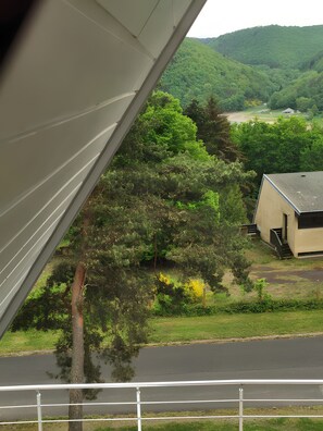 A view of a building with a sloped roof, surrounded by lush greenery and a hilly landscape. - Chalet “Le Tipi des Combrailles”: Mountain View, Private Terrace, Air Conditioning (Miremont)