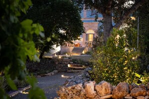 A stone pathway leading to a building with a grand staircase and a tree in the foreground.