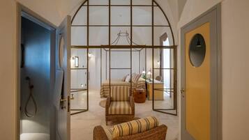 Une pièce comprenant un lit, une chaise, un bureau et une grande fenêtre en arc de cercle.