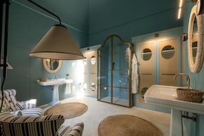 A bathroom with a glass-enclosed shower, two sinks, and a hanging lamp. - Palazzo Ceraselli (Martina Franca)