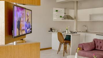 Una sala de estar moderna con un televisor de pantalla plana, un sofá rosa y una mesa de centro blanca.