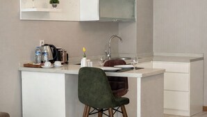 A modern kitchen with white cabinetry, a built-in stove, and a dining area with a white table and a single chair.