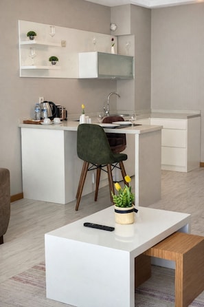 Una cocina moderna con armarios blancos, estufa integrada y un comedor con mesa blanca y una sola silla.