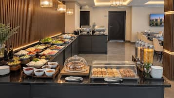 Montaje de bufé con diferentes opciones de comida y una estación de café.